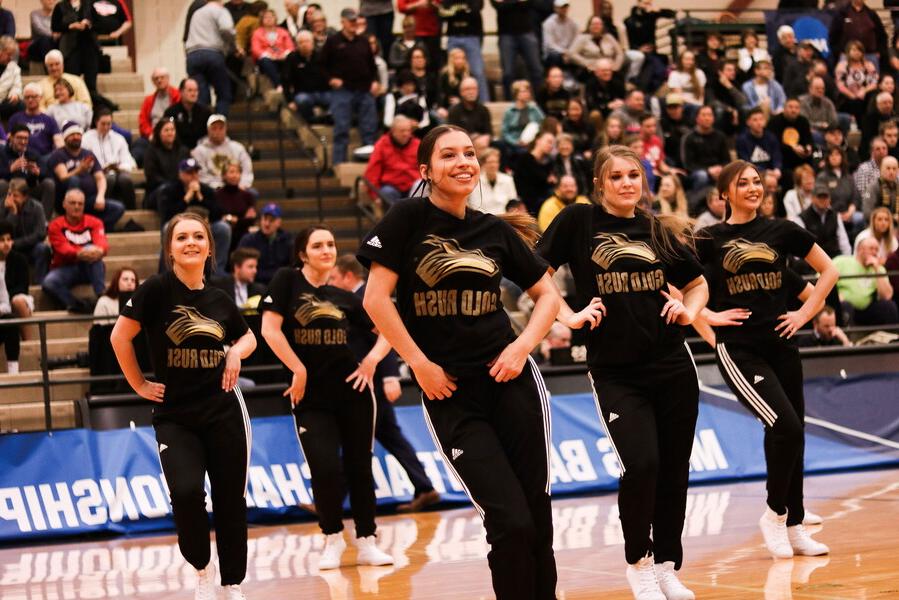 Five females of the Gold Rush dance team perform during half-time at a basketball game..